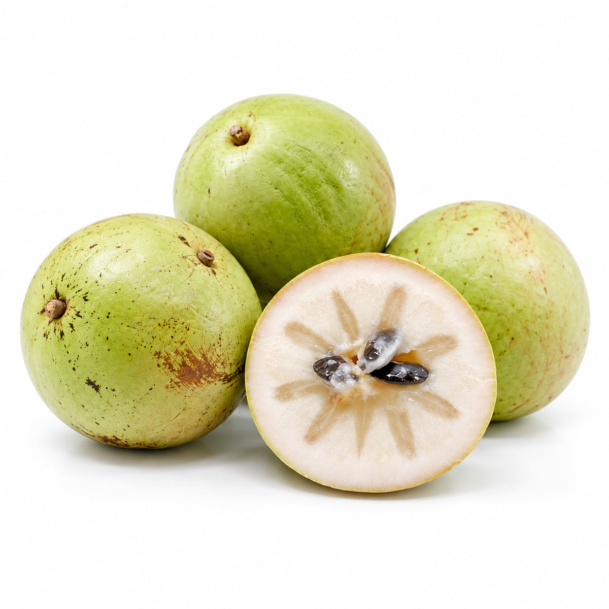Green Star Apple cut open to show the flesh on a white background